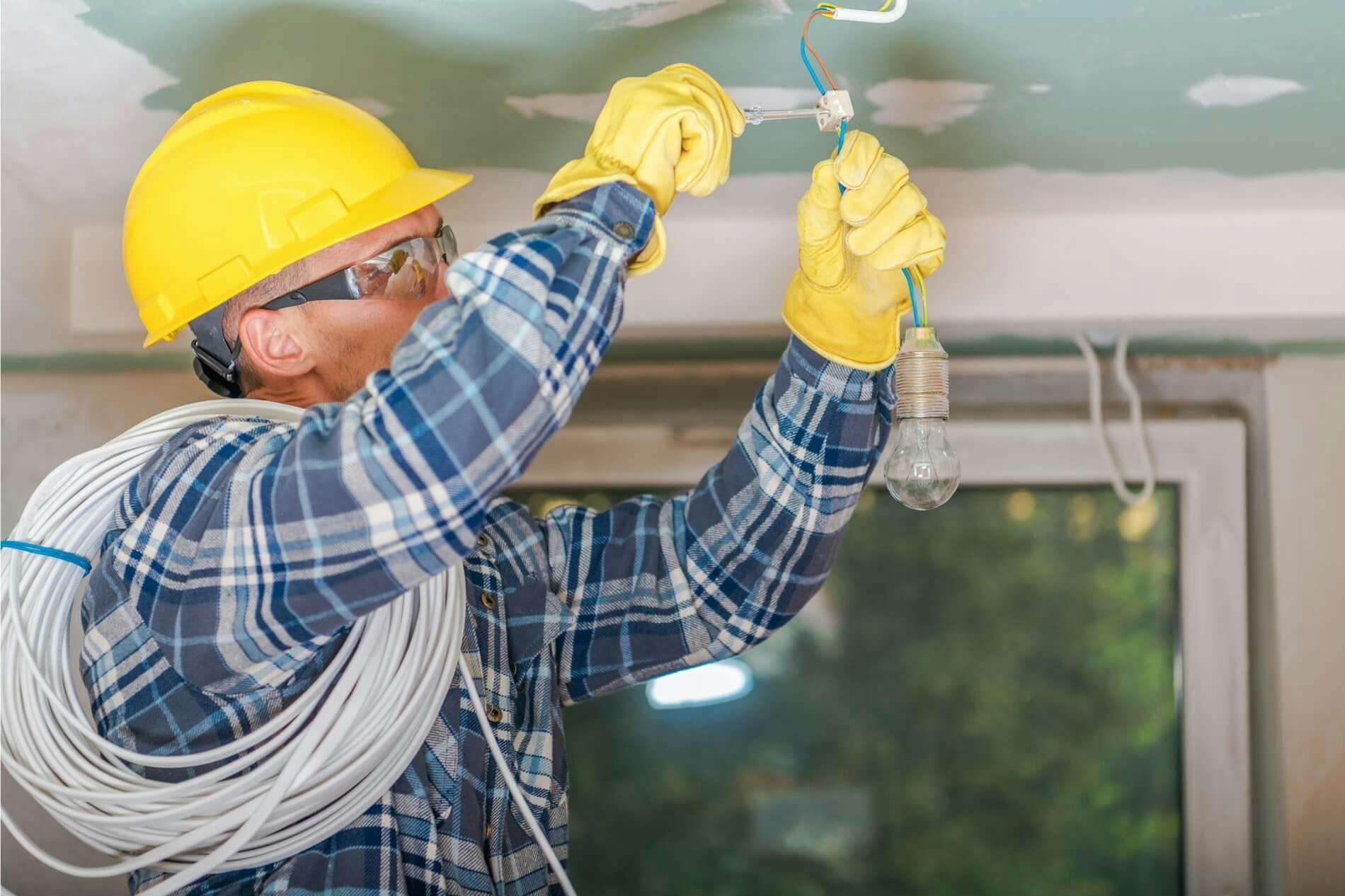 Electrician secures wires into incandescent light bulb