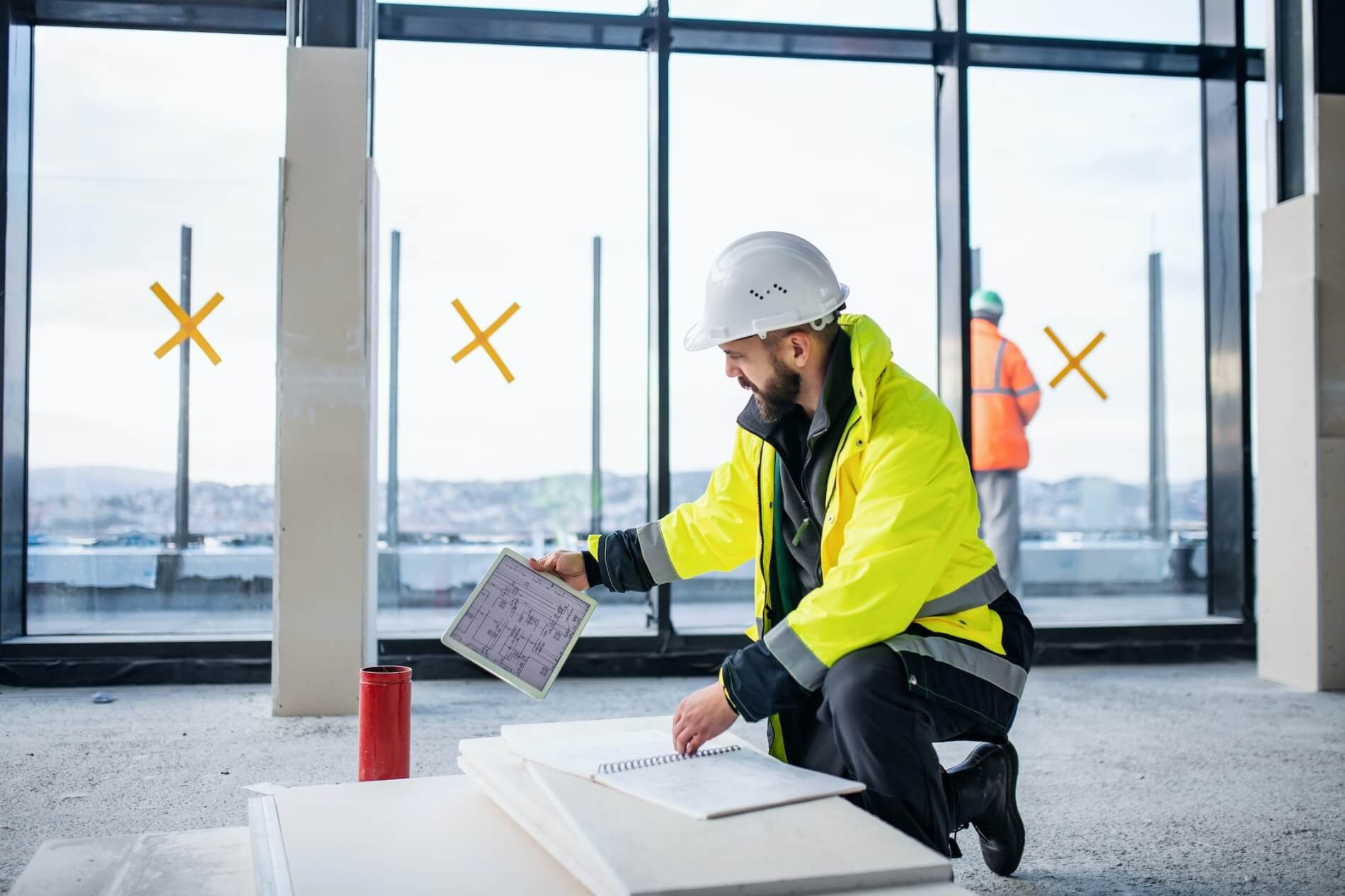 Electrician reviews blueprints on iPad and writes a plan