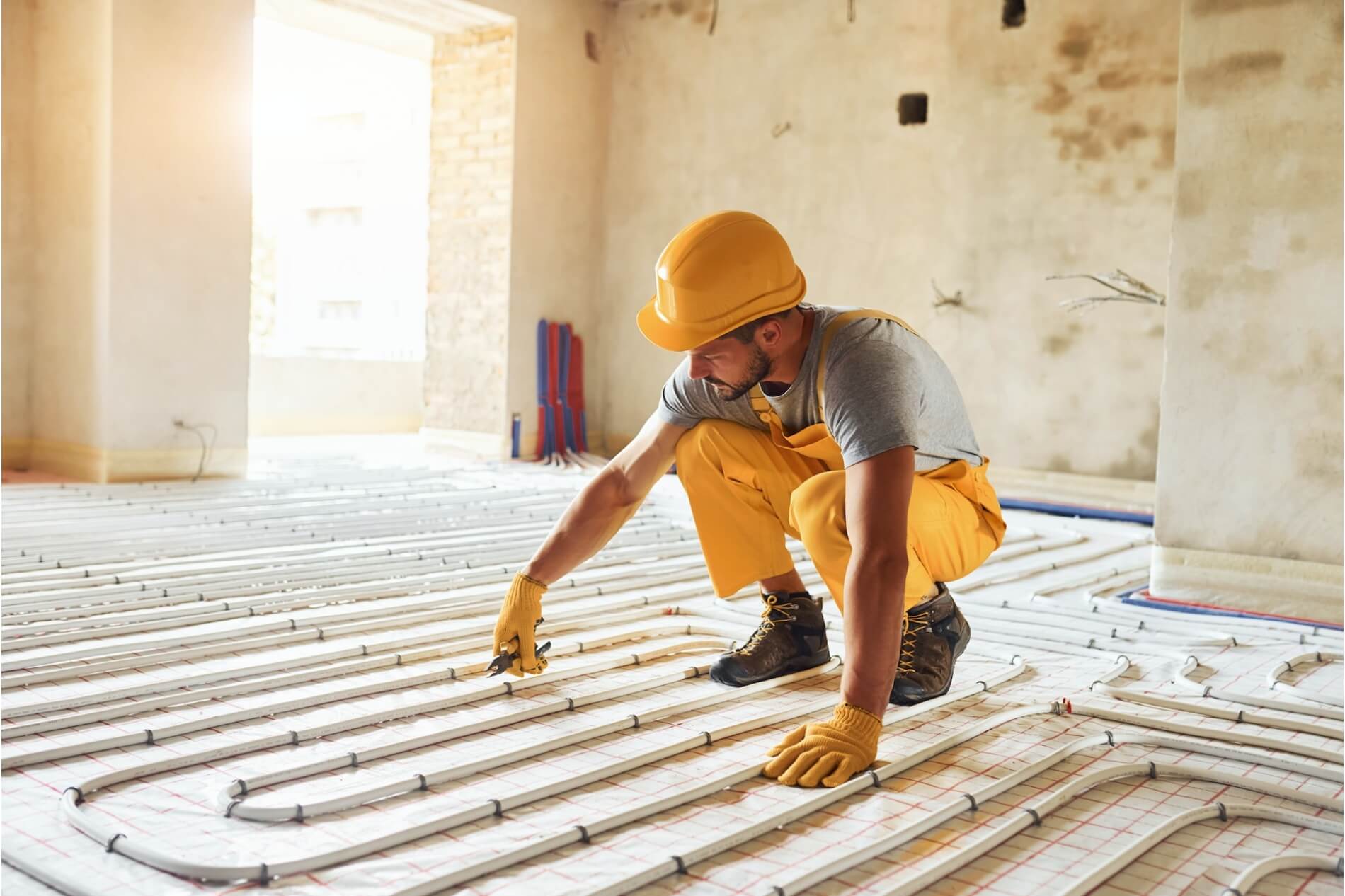 Electrician works on installing underfloor heating cables